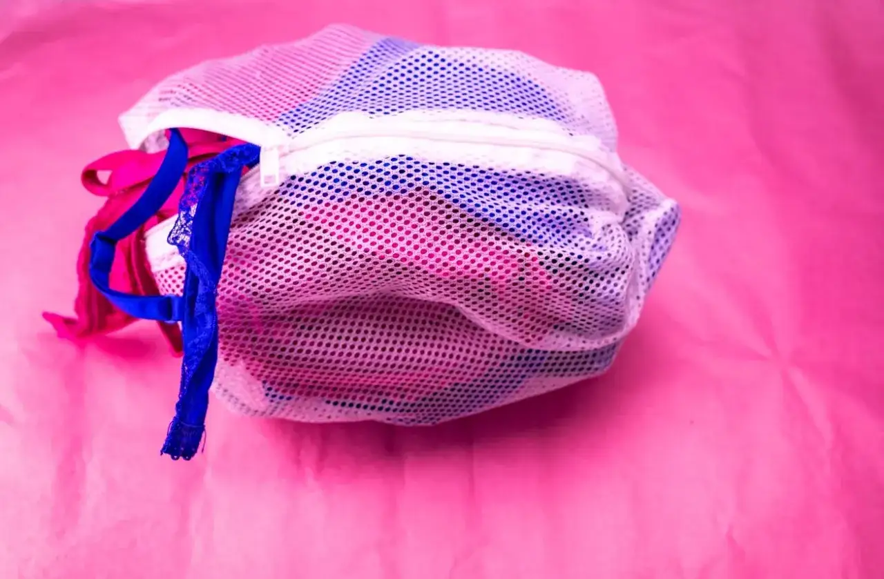 Sacchetto a rete bianco pieno di biancheria intima colorata, pronto per lavare biancheria intima in lavatrice.