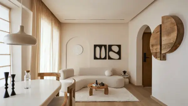 Soggiorno in stile minimalista con divano curvo, tavolino in legno e decorazioni astratte.