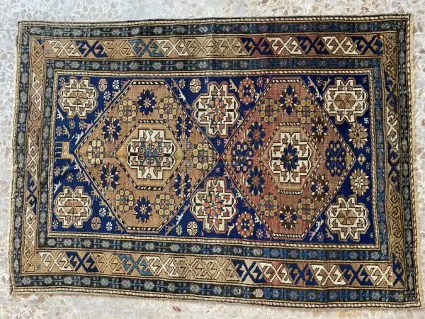 Tappeti Shirvan con motivi geometrici esagonali e floreali su sfondo blu e marrone. Bordi decorati con motivi a zig-zag.