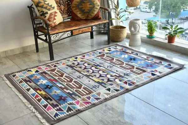 Tappeto kilim colorato con motivi geometrici. Il suo significato è legato alla tradizione tessile, un'arte che racconta storie attraverso i disegni.