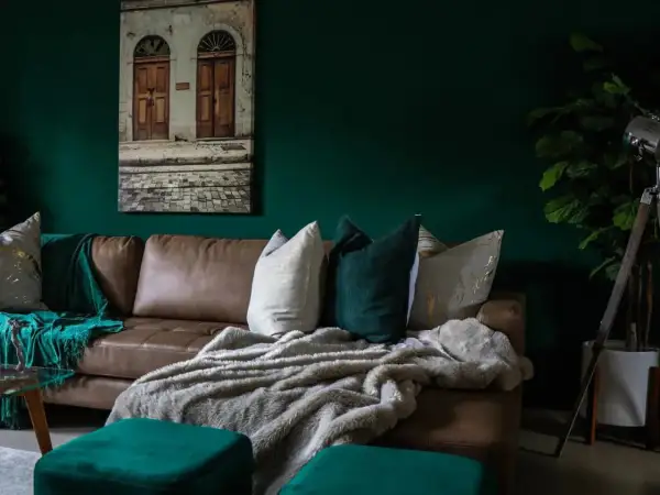Divano in pelle marrone con cuscini decorativi e coperte morbide, che creano un'atmosfera accogliente. Diversi tipi di pelle e tessuto si combinano per un look sofisticato.