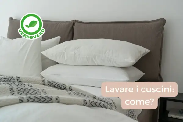 Bianchi cuscini su un letto, pronti per essere lavati in lavatrice. Scopri come lavare i cuscini per un sonno fresco e igienico.