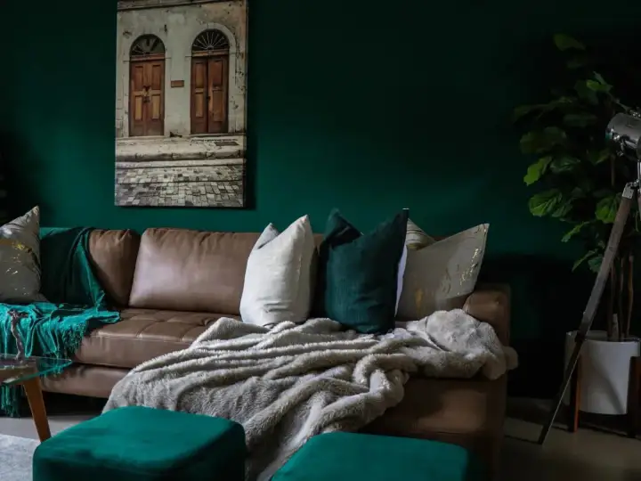 Divano in pelle marrone con cuscini decorativi e coperte morbide, che creano un'atmosfera accogliente. Diversi tipi di pelle e tessuto si combinano per un look sofisticato.